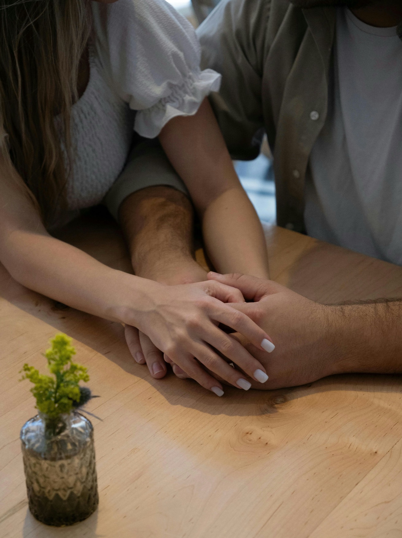 Couple's hands gently clasped together across a wooden table, representing couples therapy in San Francisco, California